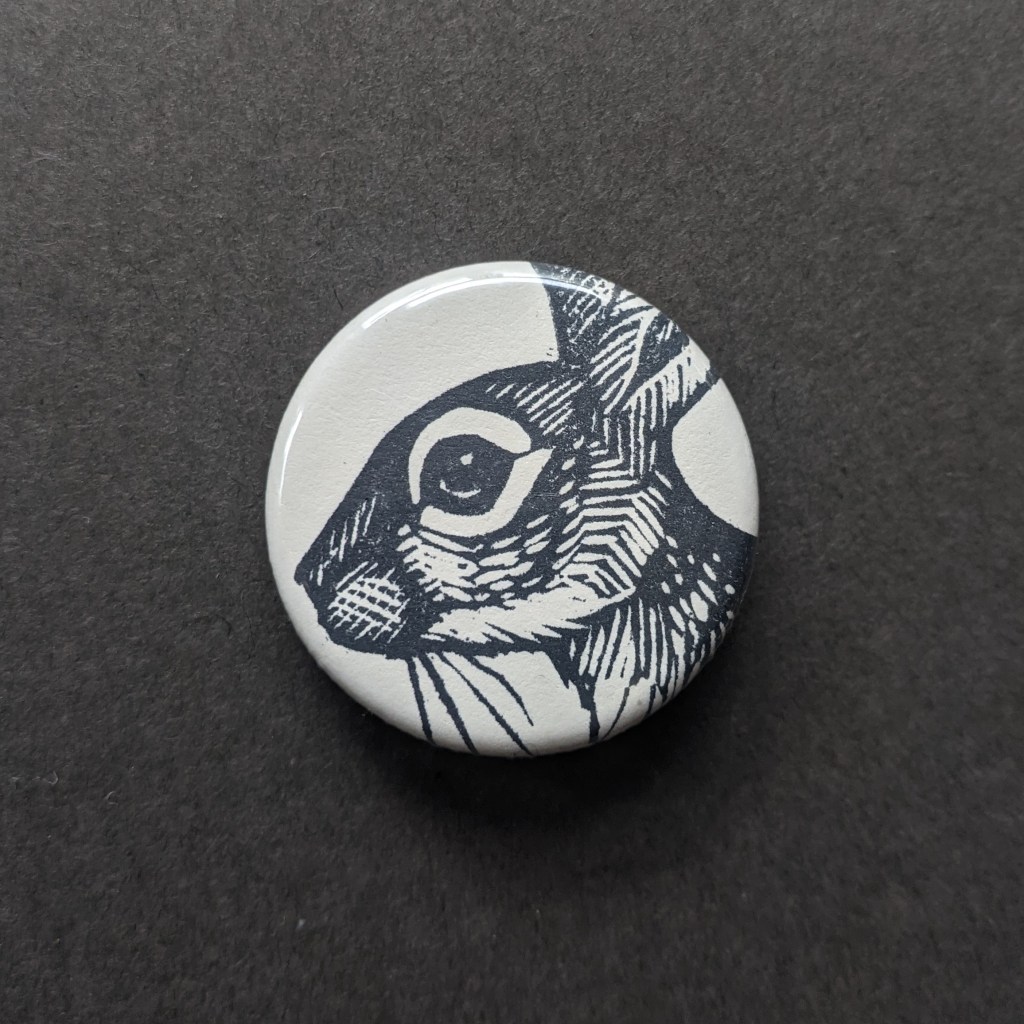 a pinback button, stamped with a hand-carved stamp of a rabbit
