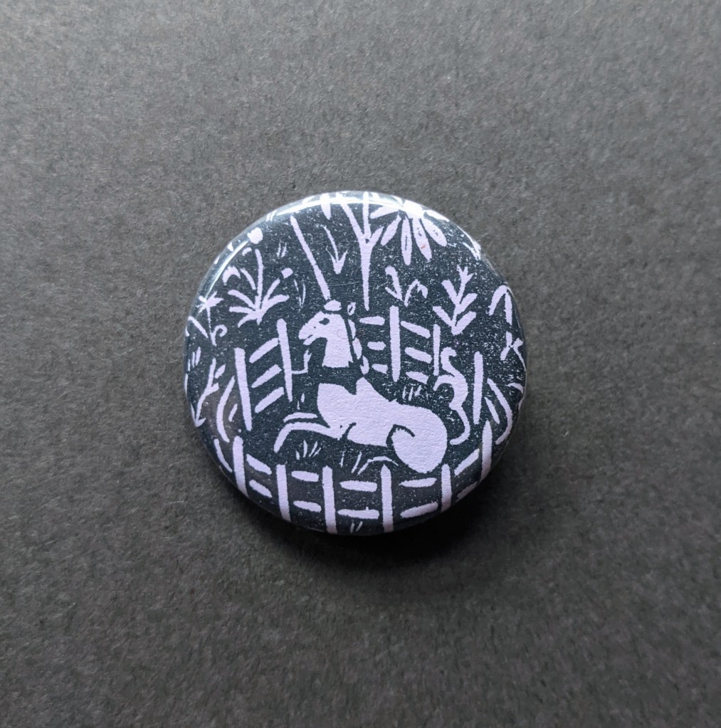 a pinback button stamped with a hand-carved stamp inspired by the unicorn tapestry