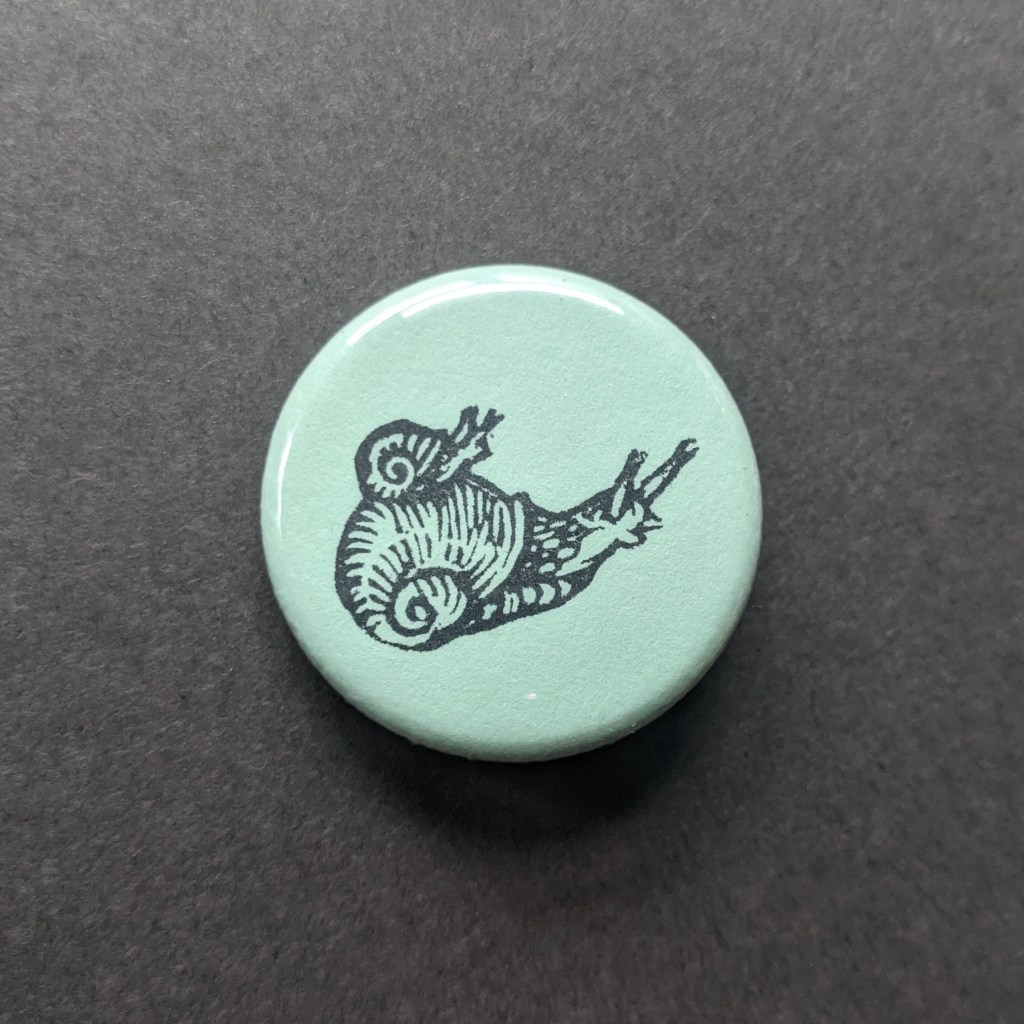 a stamped button depicting a tiny snail riding a small snail