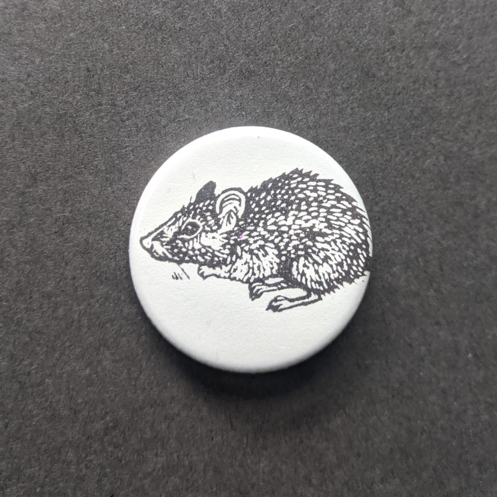 pinback button stamped with a small rat