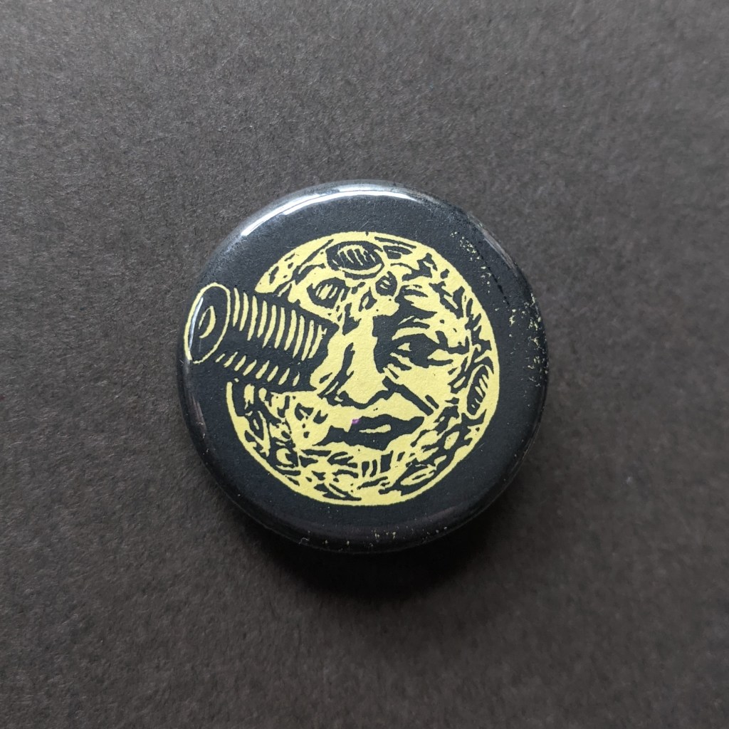 stamped button of the moon face from the old timey film "a trip to the moon"