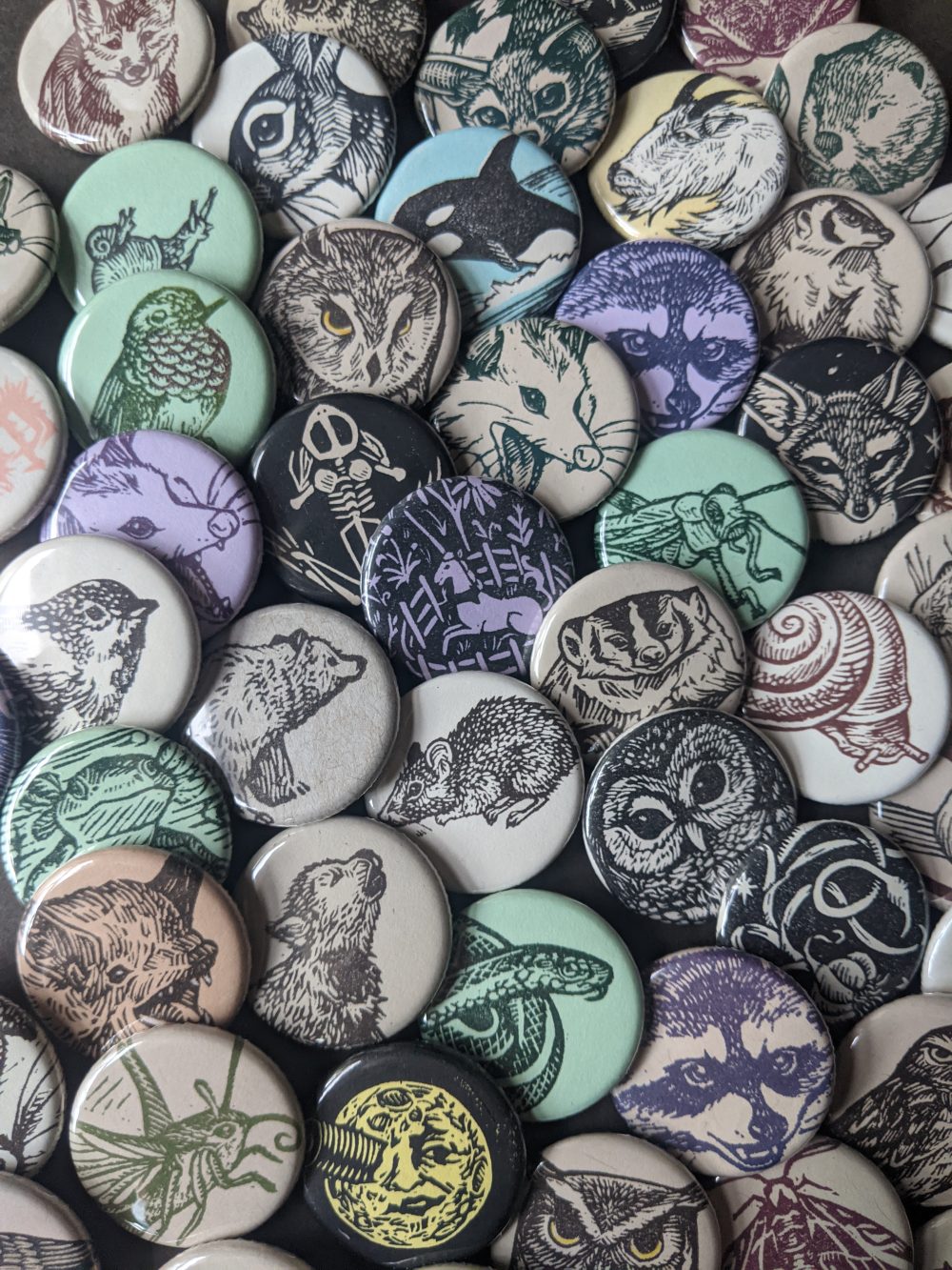 A pile of assorted buttons made with hand carved stamps, mostly wildlife themed