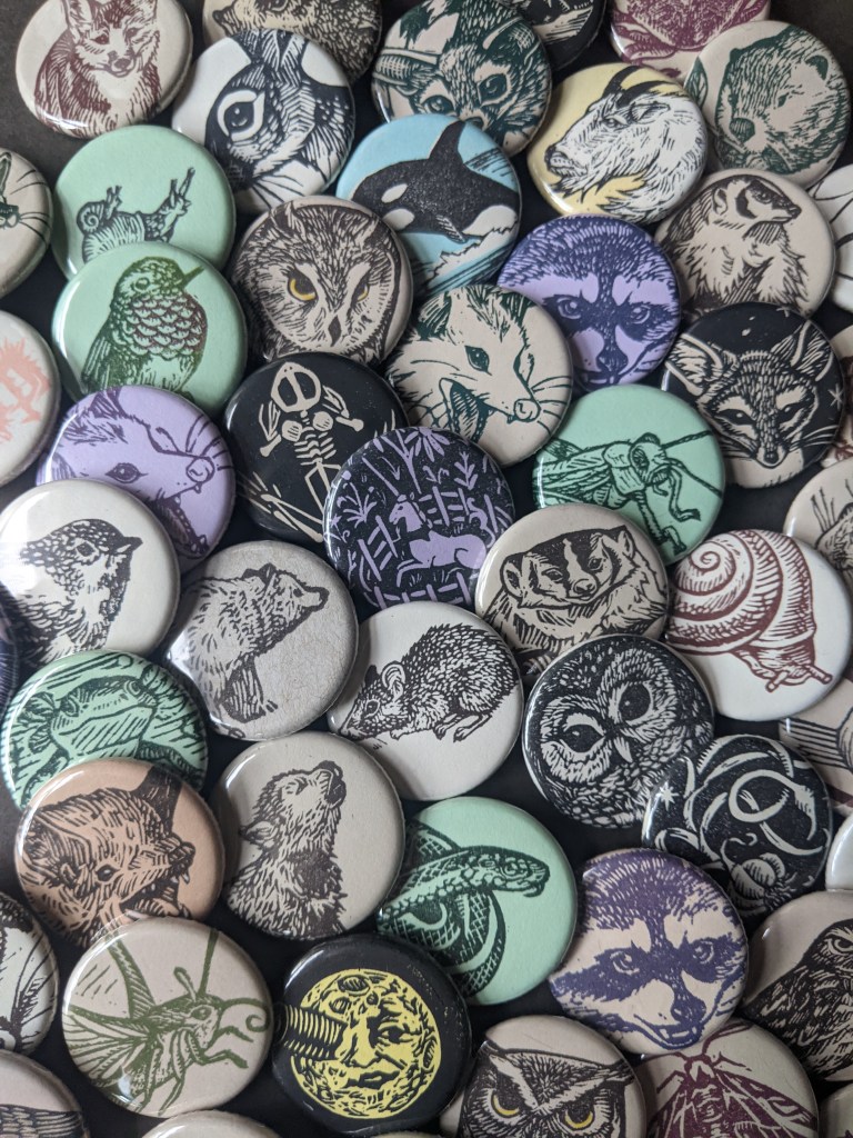 A pile of assorted buttons made with hand carved stamps, mostly wildlife themed